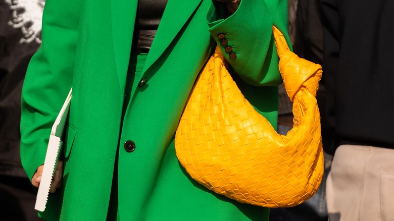 Stylish woman in loose dress suit holds Bottega Veneta Jodie bag