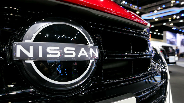 A closeup of the Nissan logo on a car at a dealership.