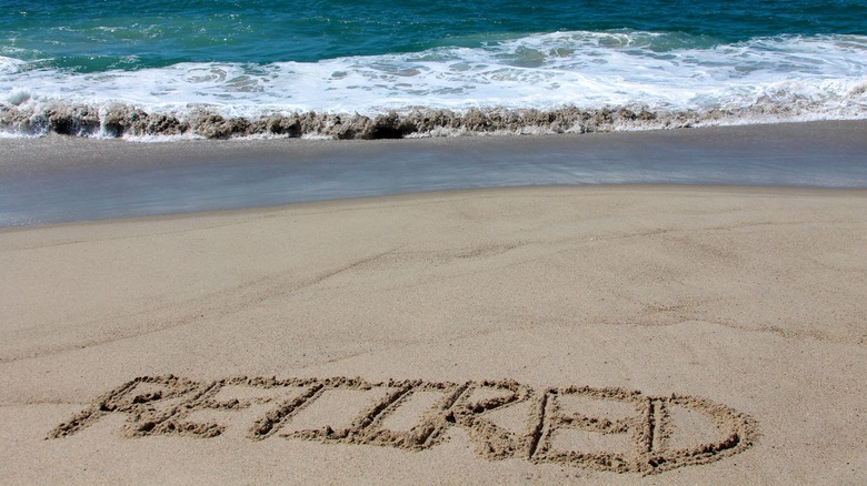 retired written in sand on beach