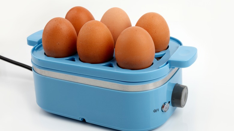 An egg cooker with six eggs on top