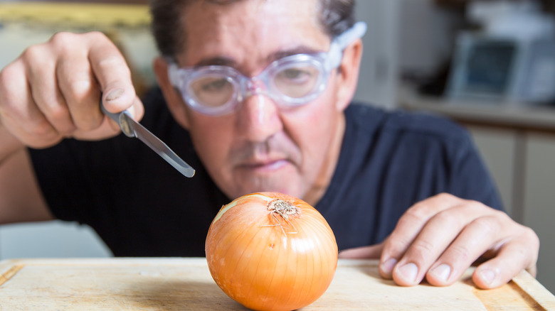 Man wears goggles while preparing to slice an onion