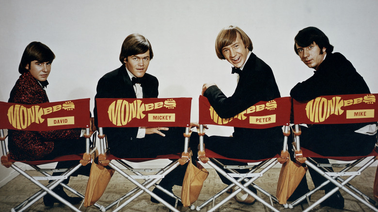 The Monkees David, Mickey, Peter, and Mike seated in red and yellow director's chairs