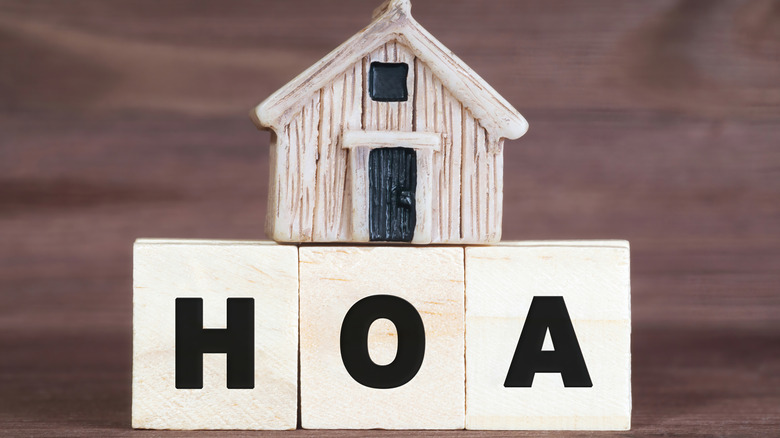 A model home on top of wooden blocks spelling out HOA.