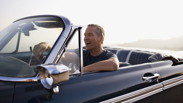 Senior man driving a luxury convertible car.