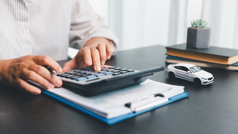 A person calculating the price of a car at a desk.