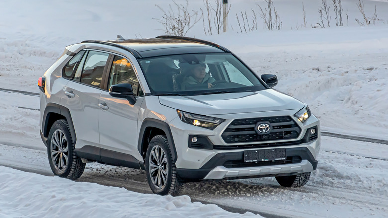 A white Toyota RAV4 driving through the snow.