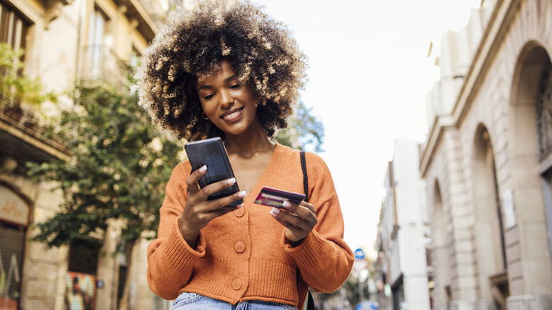 Young woman holding phone and credit card