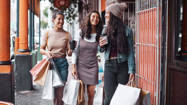 three young women carrying bags and coffee