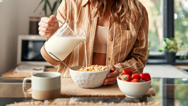 Woman pours milk into a bowl of cereal