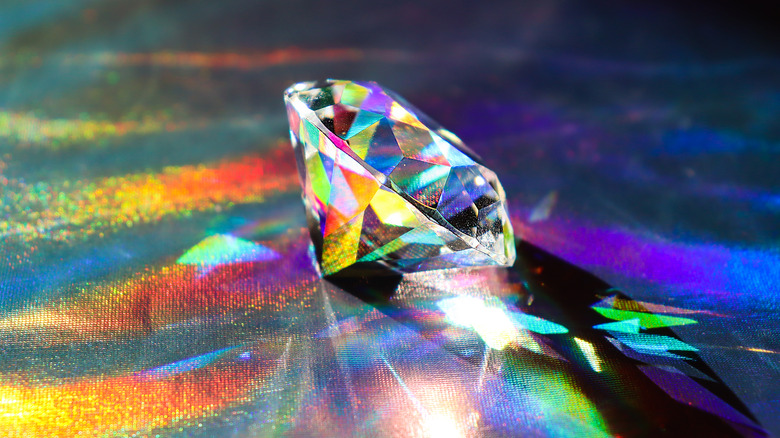 A diamond shining with a variety of colors reflecting against dark surface