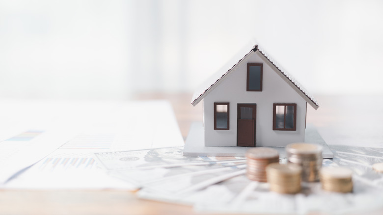 Small paper house with money and coins on table