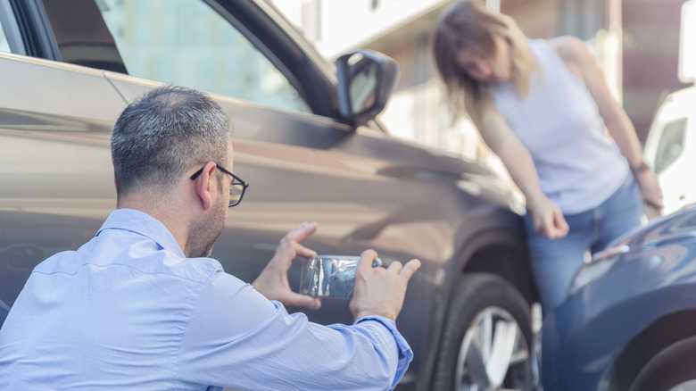 Two motorists taking pictures of accident damage