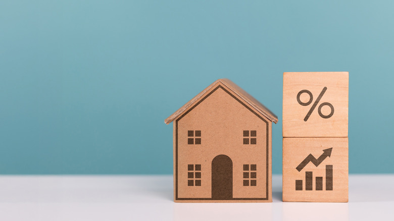 Close-up on home buying and financial analysis theme showing a wooden house with percentage blocks