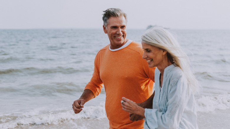 A happy senior couple walking along a Californian beach together.