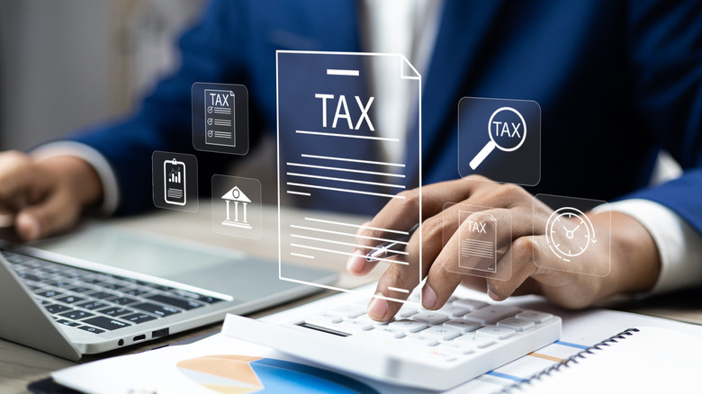 Businessman using calculator and laptop to complete Individual income tax return form.