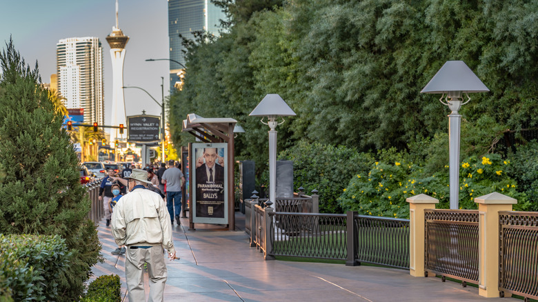 A senior man walks along Las Vegas Boulevard in the evening, with the Stratosphere Hotel and Casino in the distance.