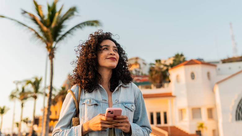 young millennial woman outside with palm tree in background