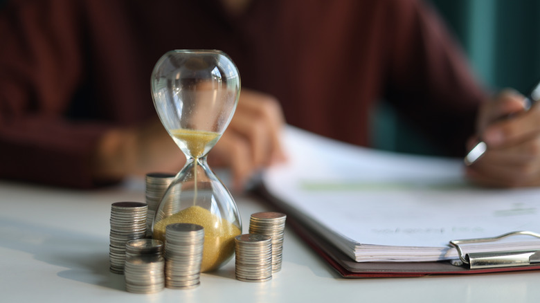 Coin stacks and sand clock on the table, symbolizing retirement planning.