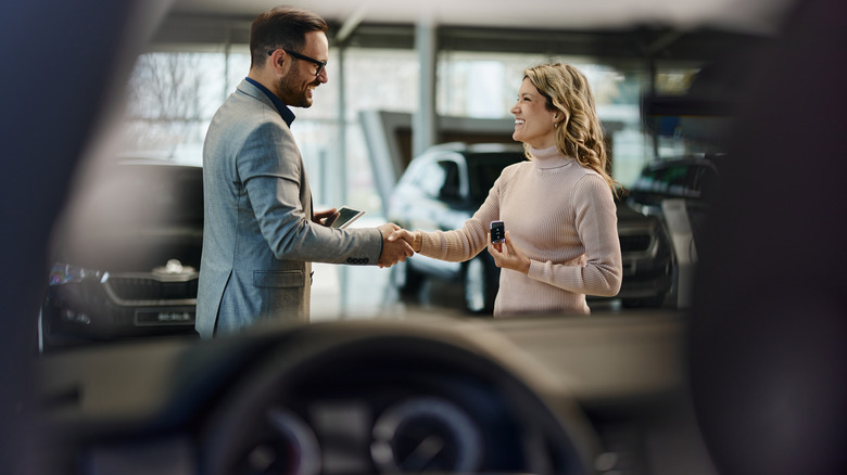 A car salesman shaking a woman's hand
