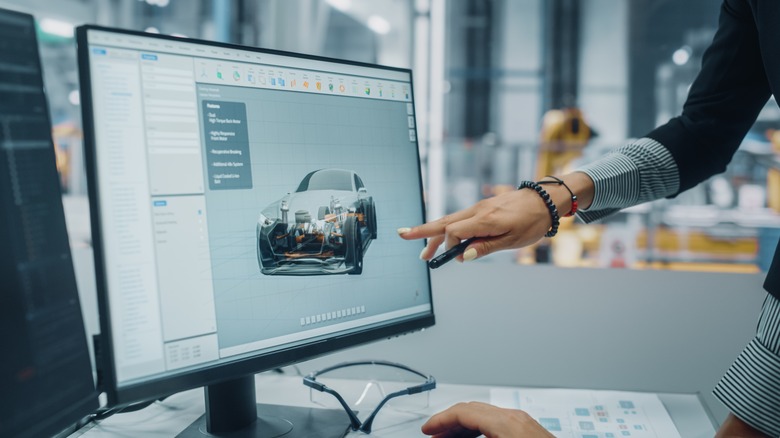 A woman's hand pointing at a screen displaying a vehicle