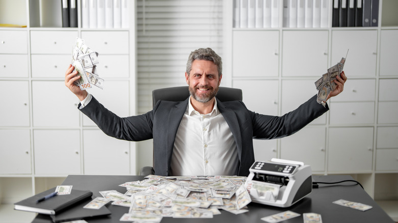 guy sitting with a money counter and lots of money
