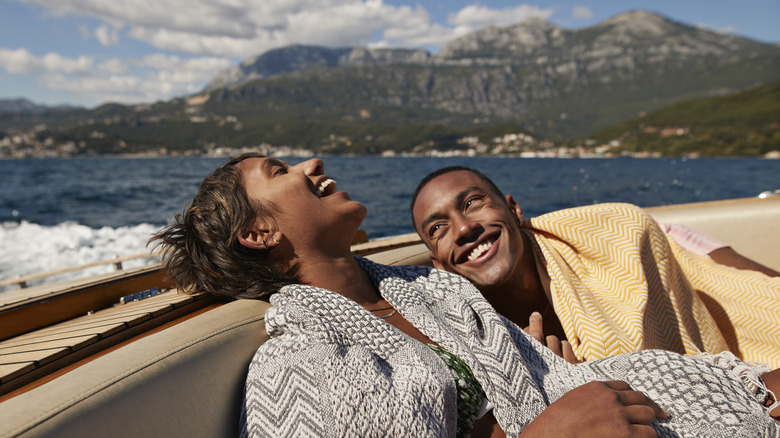 Young man and woman laughing in speedboat enjoying summer on sunny day.