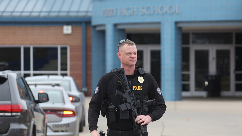 An Iowa police officer standing outside a high school