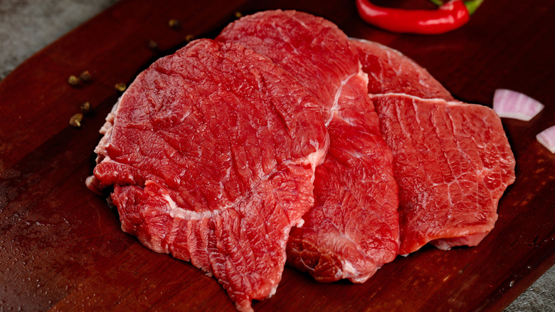 Bottom round steak slices on a wooden board.
