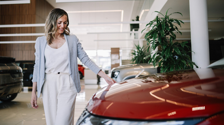 Mid aged woman visits the car dealership, looking at the current offers