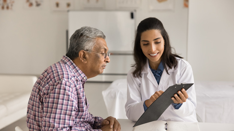 Older male patient looking over a chart with a younger doctor