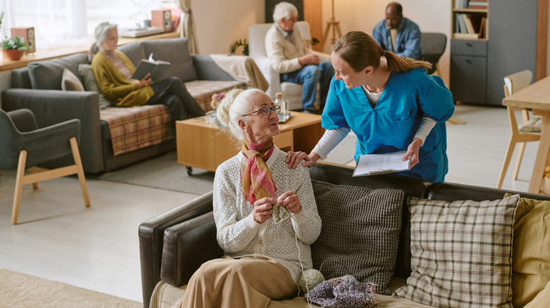 High angle shot of nurse communicating with senior woman as she crochets
