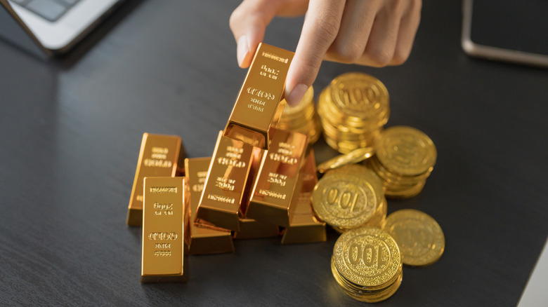 Person selecting gold bar with coins.