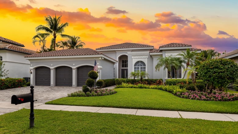 A home with a perfectly manicured lawn with palm trees in the background.