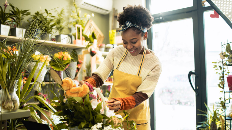 A young woman trimming flowers in florist shop