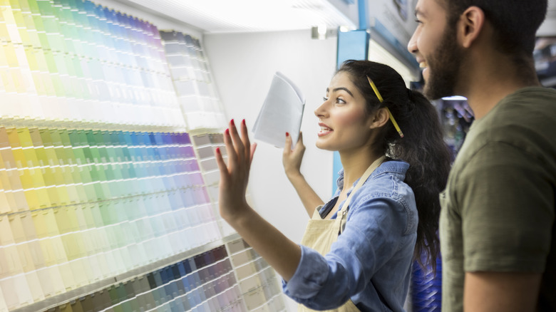 A paint store employee showing paint samples to a man