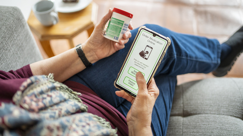 An elderly woman ordering medication online with a phone