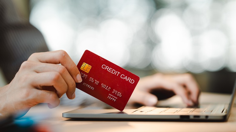 holding a credit card near laptop