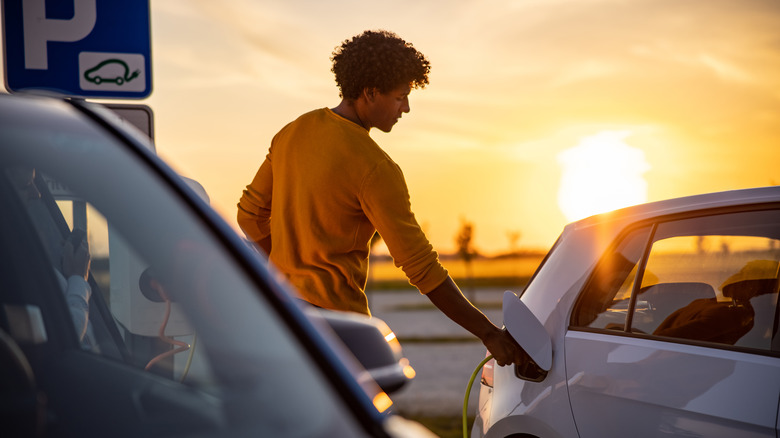 A man charging his EV as the sun sets.