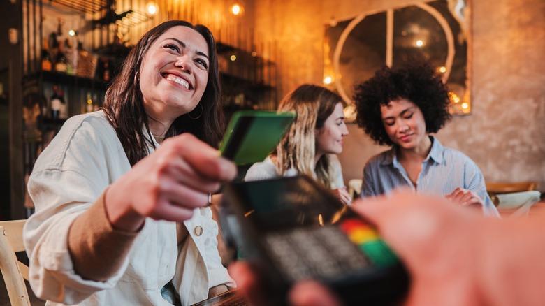 A smiling woman holding a credit card