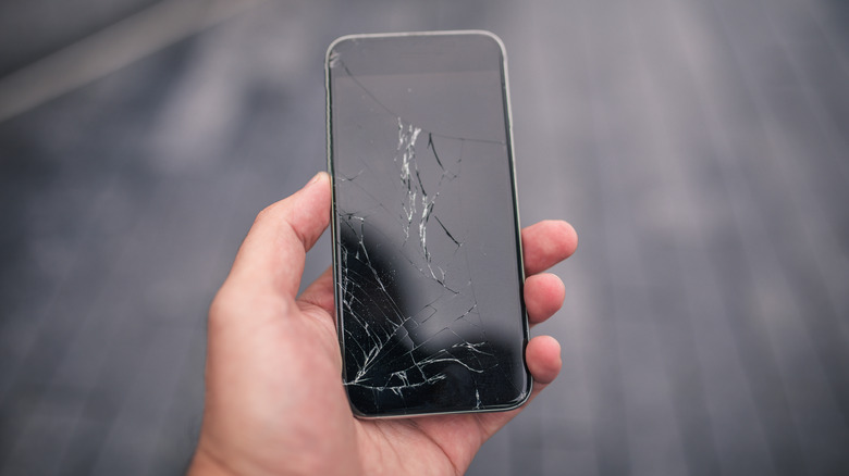 A hand holding a broken cellphone