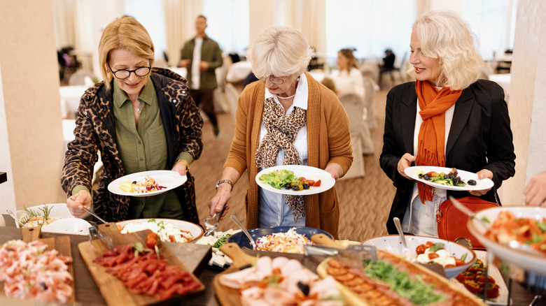 Three elderly women at a buffet