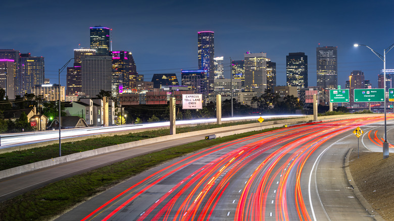 Houston downtown with car vehicle light tail on highway traffic to downtown district at night with skyscraper modern business office in Houston city in Texas, USA.