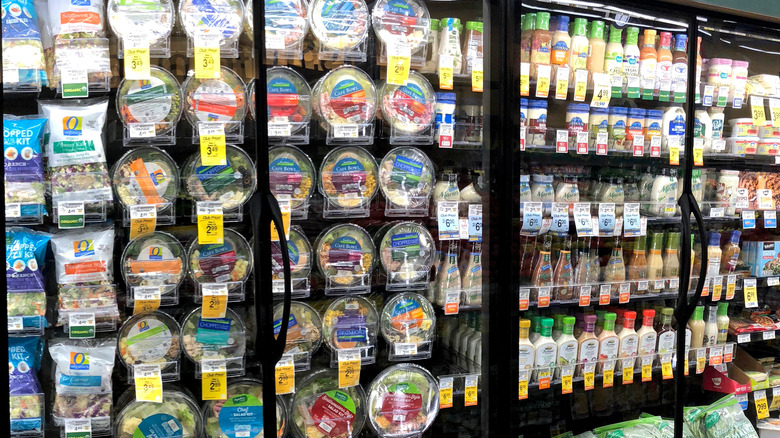 salad mixes in a case with salad dressing