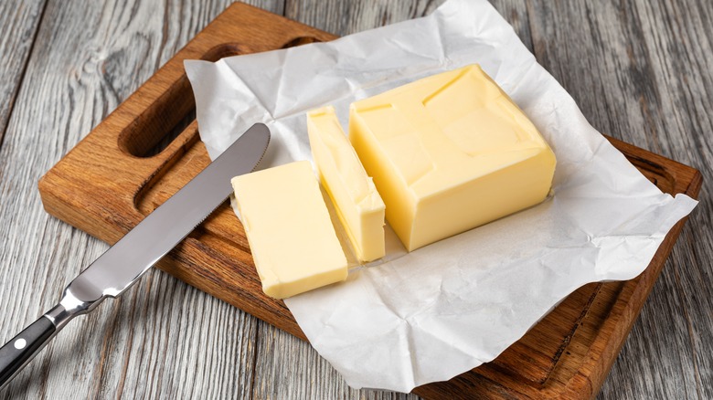 Open and sliced sticks of butter with butterknife on top, resting on cutting board