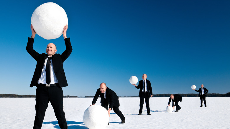 man in suit rolling snowballs