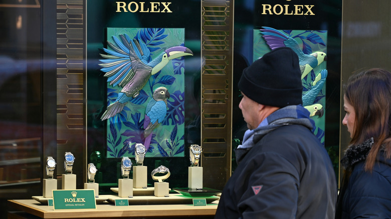 A couple looking in the window at a display of Rolex watches