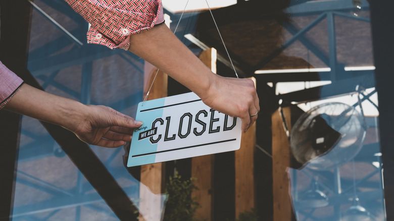 Employee putting closed sign on business door