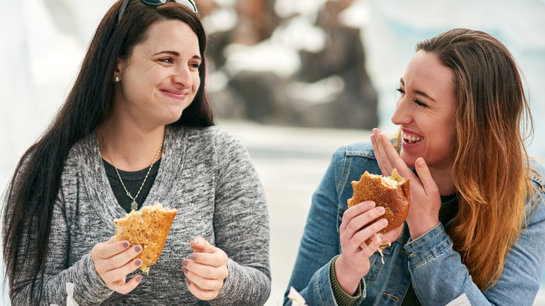Two women eating sub sandwiches