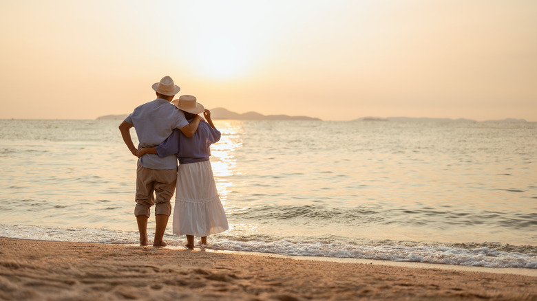 A senior couple standing on beach