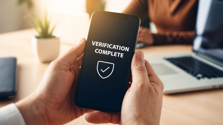 Hand holding smartphone displaying verification complete message